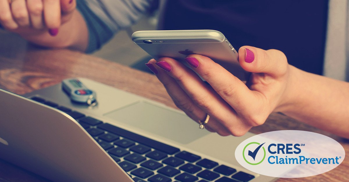 woman at desk holding smart phone