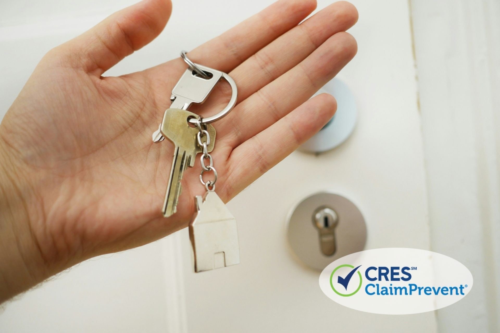 hand holding keys on keychain in front of door